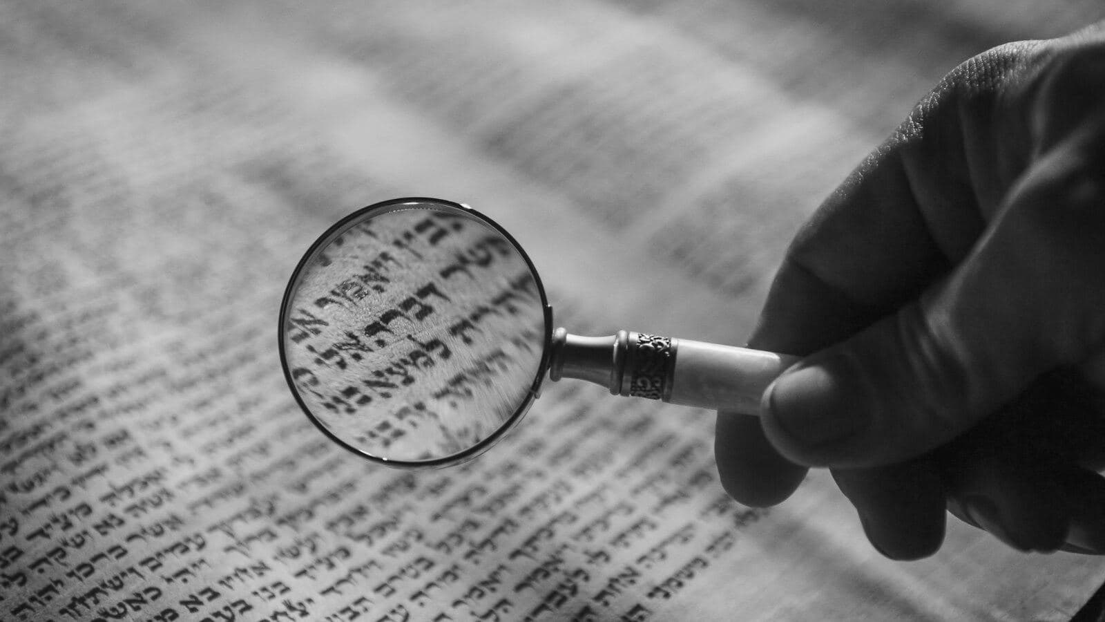 Una mano sostiene una lupa sobre un texto