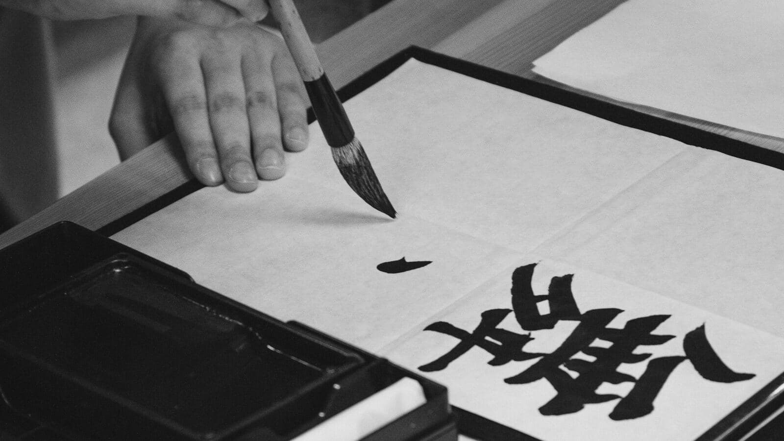 Una mano escribiendo caligrafía con pincel y tinta