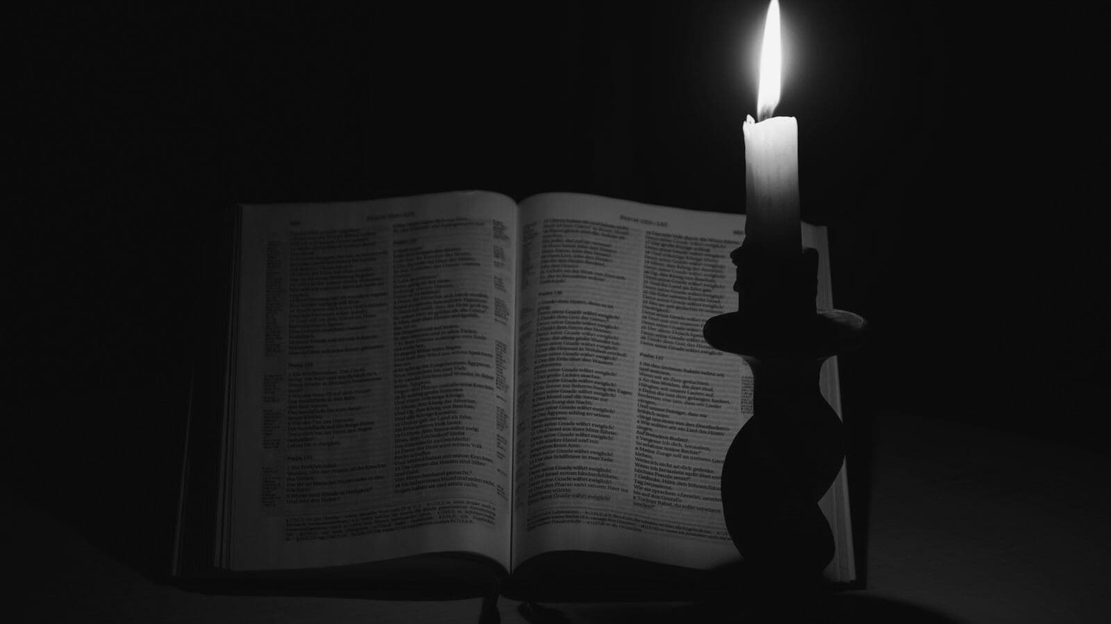 Un libro abierto junto a una vela encendida